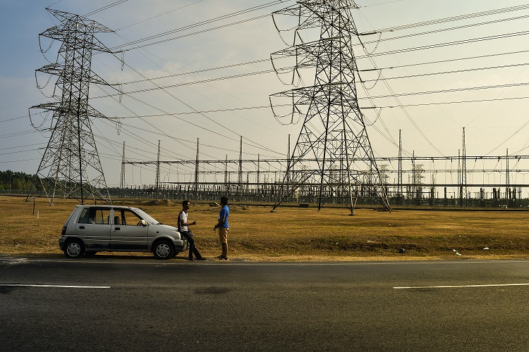 Two men talking by the roadside next to power lines in Sungai Petani, Kedah, Malaysia. | Photo by Ravin Rau on Unsplash