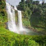 Great waterfall scenery with a rainbow. Tad Yuang, dramatic waterfall drops 40 metres over a cliff and tropical forest. Bolaven Plateau, Paksong, Laos. Rainy season.
