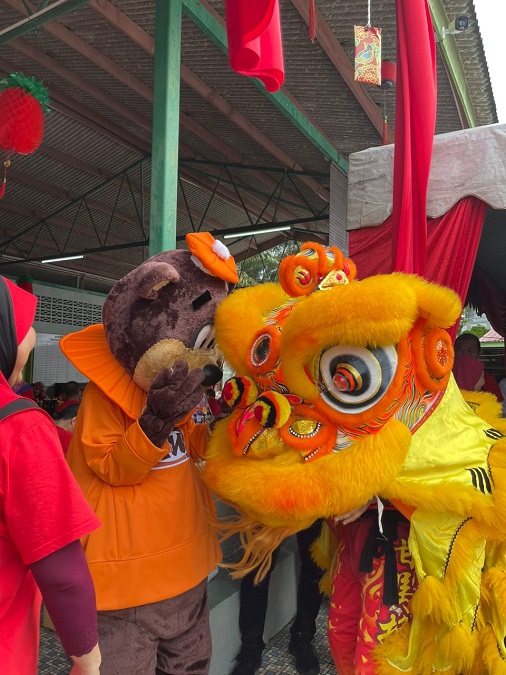 A&W's mascot, Rooty the Great Root Bear, sharing a light-hearted moment with one of the lions at the Lynas Malaysia's Chinese New Year 2023 celebration. | Jabor Old Folks Home, 4 February 2023 | NHA File Photo