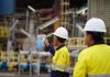 In the foreground are two employees of Lynas Malaysia wearing their usual safety uniforms at work in the plant at the Gebeng Industrial Park in Kuantan, Pahang, Malaysia. | Photo by Lynas Malaysia/cropped/NHA File Photo