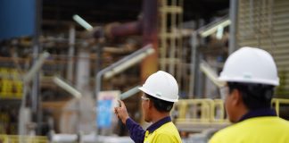 In the foreground are two employees of Lynas Malaysia wearing their usual safety uniforms at work in the plant at the Gebeng Industrial Park in Kuantan, Pahang, Malaysia. | Photo by Lynas Malaysia/cropped/NHA File Photo