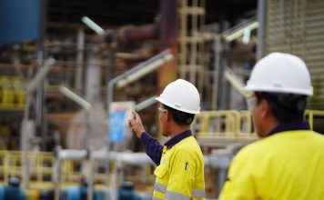 In the foreground are two employees of Lynas Malaysia wearing their usual safety uniforms at work in the plant at the Gebeng Industrial Park in Kuantan, Pahang, Malaysia. | Photo by Lynas Malaysia/cropped/NHA File Photo