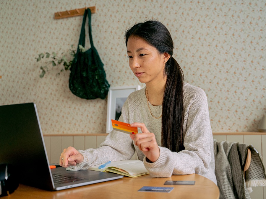 Woman holding bank card in front of her laptop to perform online banking transaction. | Photo for illustrative purposes only. | Photo by Antoni Shkraba/Pexels/NHA File Photo