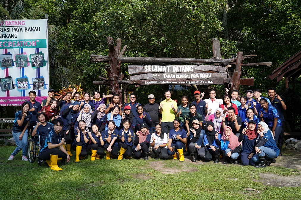 Lim Cheong Guan (Managing Director, Top Glove) [standing, centre, in light green shirt], flanked by Tuan Suhaimi bin Sanusi (Community Head, SMRP) [standing, left] and Sharmila Sekarajasekaran (Senior Independent Non-Executive Director, Top Glove) [standing, right], along with Top Glove staff volunteers, gather for a group photo before the mangrove planting event at Sijangkang Mangrove Recreational Park (SMRP). | Photo by Top Glove/NHA File Photo