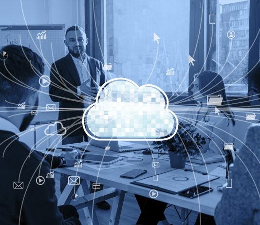 Conceptual photo of cloud computing. In the centre is a drawing of a cloud with arrows out to indicate a network connected online. In the background is a group of business people in a discussion in a meeting room and the entire photo has a blue filter. | Photo by Freepik/NHA File Photo