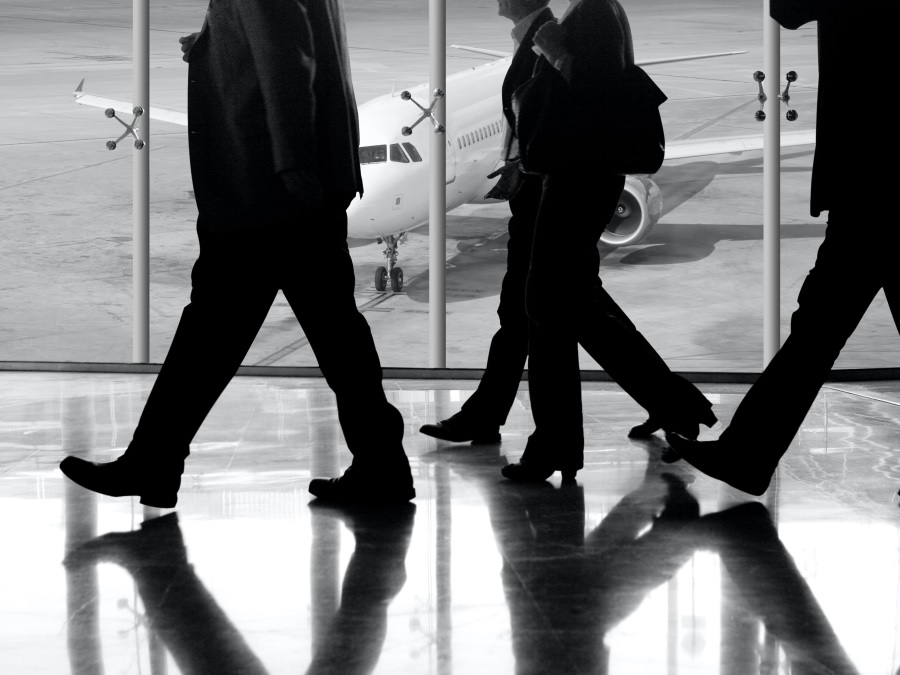 Silhouettes of business travellers walking in the airport by the window with an airplane in view in Valencia, Spain, 9 October 2020. | Photo by Rob Wilson/Unsplash/NHA File Photo