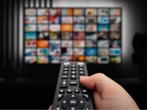 VOD service screen. A man watching videos on demand on TV with remote control in hand. | Photo by Proxima Studio via Canva Pro / NHA File Photo