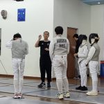 Coach Mok speaking with fencers before open sparring session