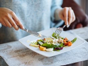 Woman's hands with Caesar salad on table in restaurant. Photo for illustrative purposes only. | Photo by Sunway Medical Centre / NHA File Photo