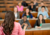 A multi-ethnic group of students listening to a lecture from a Professor standing in front of the class in a lecture hall. | Photo by FatCamera from Getty Images Signature (via Canva Pro) / NHA File Photo