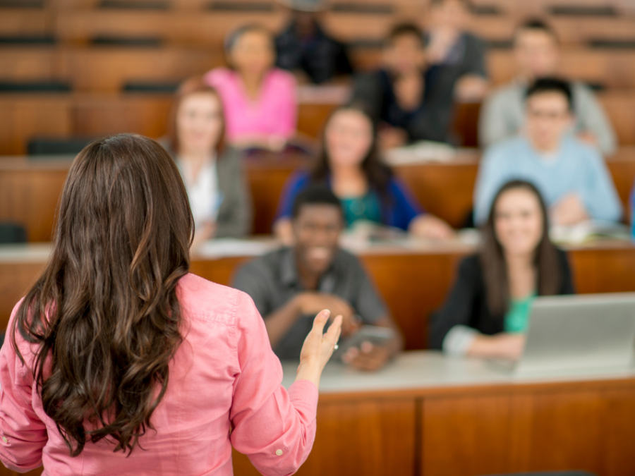 A multi-ethnic group of students listening to a lecture from a Professor standing in front of the class in a lecture hall. | Photo by FatCamera from Getty Images Signature (via Canva Pro) / NHA File Photo